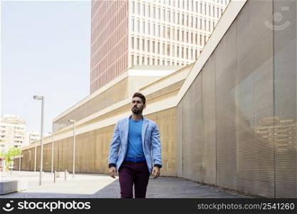 Young bearded male in casual clothes walking on the street