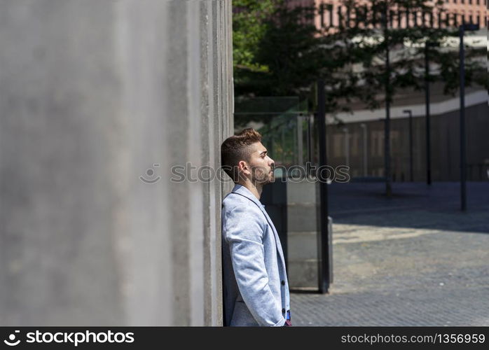 young bearded man leaning against wall and thinking