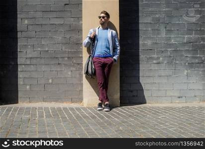 Young bearded man, model of fashion, in urban background wearing casual clothes while leaning on a office building wall
