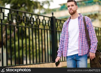 Young bearded man walking in urban background. Lifestyle concept. Young bearded man walking in urban background. Traveler wearing casual clothes. Lifestyle concept.
