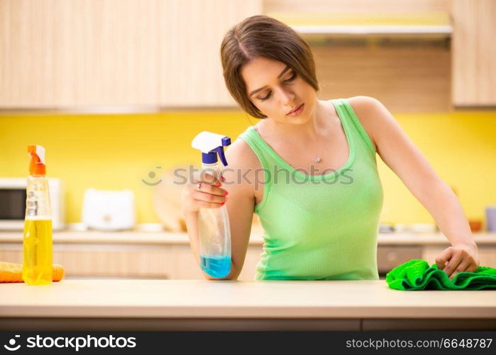 Young beatifull woman polishing table in the kitchen 