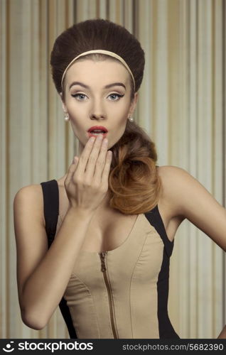 Young, beautifil retro girl in fitted cream and black dress. She has got big blue eyes, brown big hairstyle and she is wearing pearls on her ears. She is a little bit suprised.