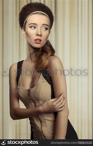 Young, beautifil retro girl in fitted cream and black dress. She has got big blue eyes, brown big hairstyle and she is wearing pearls on her ears.