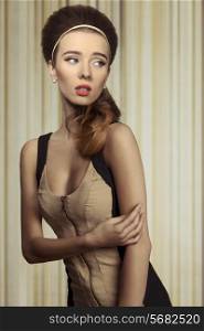 Young, beautifil retro girl in fitted cream and black dress. She has got big blue eyes, brown big hairstyle and she is wearing pearls on her ears.