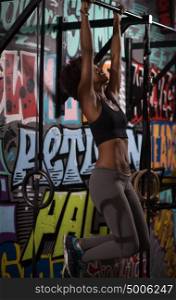 young beautiful african american woman athlete doing pull ups on the horizontal bar in the gym