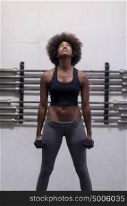 young beautiful African American woman doing bicep curls in a gym