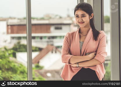 Young beautiful Asian business woman standing in office.