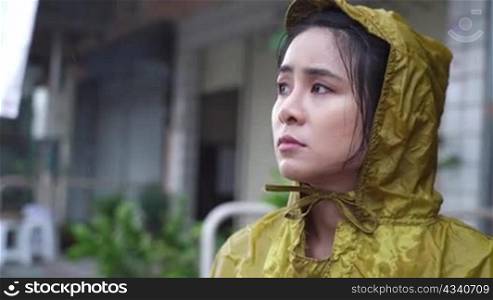 young beautiful asian female wear yellow hoody raincoat feeling sad and disappoint in the pouring rain day, rainy season weather climate, feeling blue and lonely, Bad stormy sorrow unhappy vibe