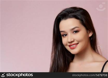 young beautiful Asian girl. smiles. on a pink isolated background.