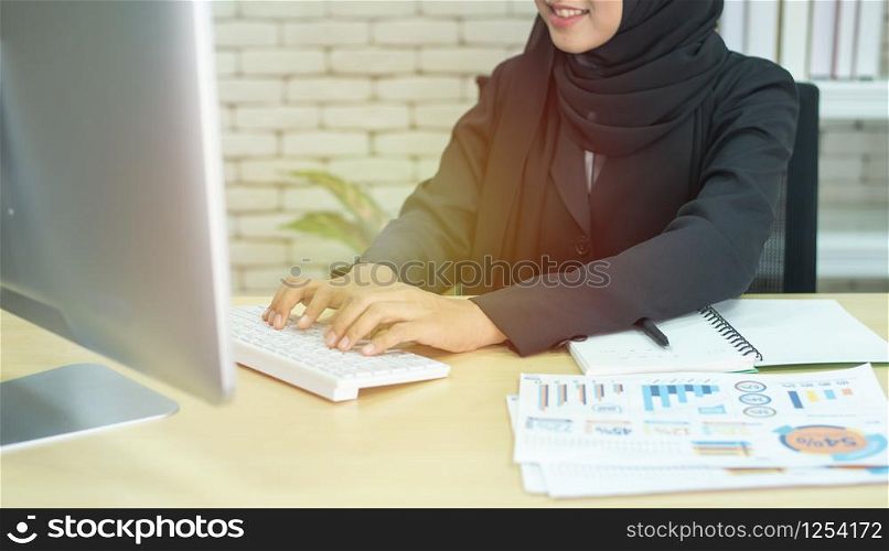 Young beautiful asian muslim business woman wearing black hijab,working at coworking place.