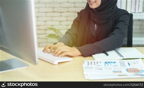 Young beautiful asian muslim business woman wearing black hijab,working at coworking place.