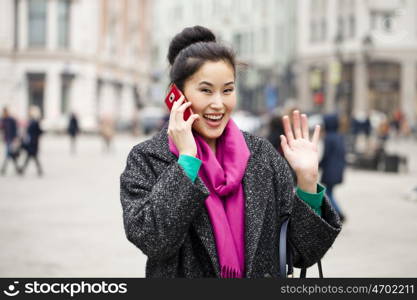 Young beautiful asian woman calling by phone on the spring street