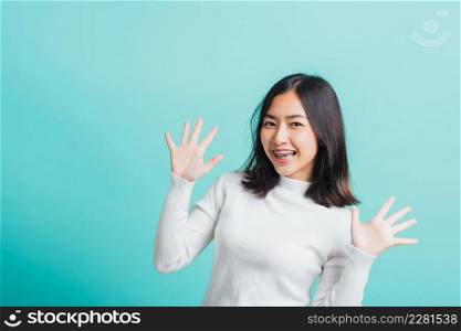 Young beautiful Asian woman cheerful smiling makeup showing open hands, Portrait happy female shocked she shows palms, studio shot isolated on a blue background