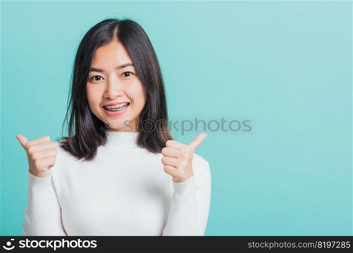 Young beautiful Asian woman cheerful smiling showing finger thumb up, Portrait happy female using showing like the gesture for good sign, studio shot isolated on a blue background