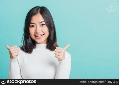 Young beautiful Asian woman cheerful smiling showing finger thumb up, Portrait happy female using showing like the gesture for good sign, studio shot isolated on a blue background