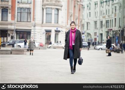 Young beautiful asian woman in stylish gray coat on a background of spring street