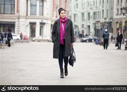 Young beautiful asian woman in stylish gray coat on a background of spring street