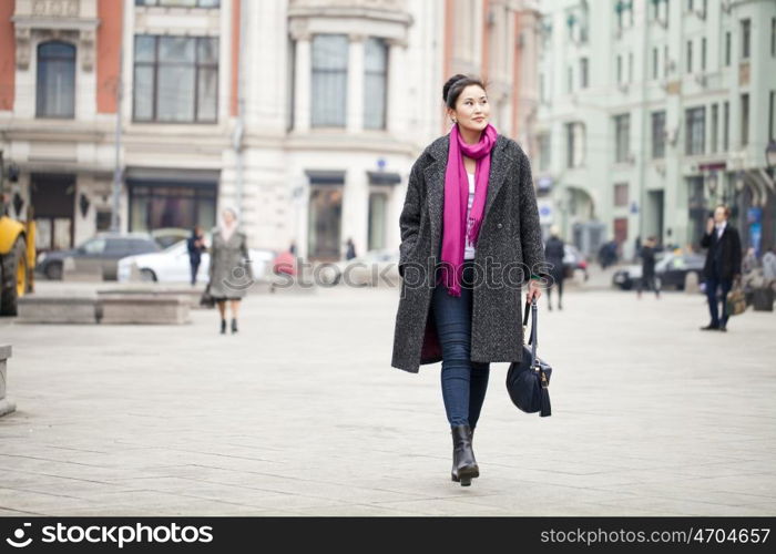 Young beautiful asian woman in stylish gray coat on a background of spring street