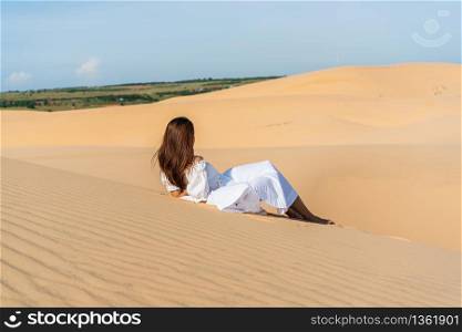 Young beautiful Asian woman posing in a white dress in white sand dune desert, Muine Vietnam.