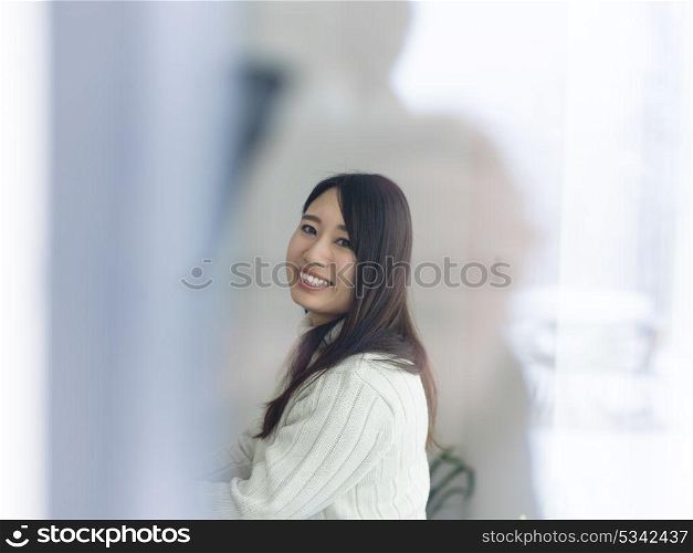 young beautiful asian woman sitting near window at cold winter day