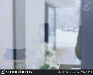 young beautiful asian woman sitting near window at cold winter day