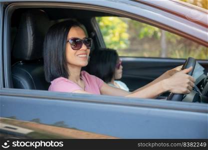 Young beautiful asian woman smiling and driving a car. Her cute daughter sitting beside and enjoying. Asia mother and daughter travel holiday long weekend with car.