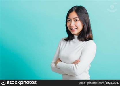 Young beautiful Asian woman smiling with crossed arms, Portrait of positive confident female stand cross one&rsquo;s arm, studio shot isolated on a blue background