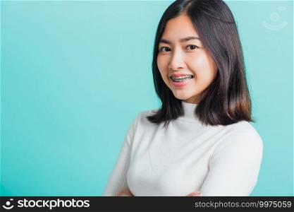 Young beautiful Asian woman smiling with crossed arms, Portrait of positive confident female stand cross one’s arm, studio shot isolated on a blue background