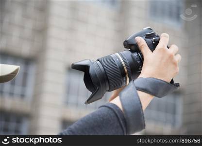 Young beautiful asian woman taking photo outdoors with DSLR digital camera. Young cheerful female tourist having fun in coffee shop. Lifestyle portrait concept.