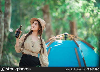 Young beautiful Asian women and friends travelers relaxing at front of c&ing tent, They enjoy to talking and drinking beer with fun and happy together