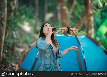 Young beautiful Asian women and friends travelers relaxing at front of camping tent, They enjoy to talking and drinking beer with fun and happy together