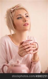Young beautiful blond woman having tea-party. She is very satisfacted. Short hair and pink colors - modern style