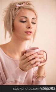 Young beautiful blond woman having tea-party. She is very satisfacted. Short hair and pink colors - modern style