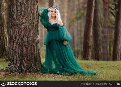 young beautiful blonde hair woman queen. Princess walks. autumn green forest mystic. Vintage medieval shiny crown. Long evening green dress. magic fantasy.. young beautiful blonde hair woman queen. Princess walks. autumn green forest mystic. Vintage medieval shiny crown. Long evening green dress. magic fantasy