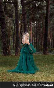 young beautiful blonde hair woman queen. Princess walks. autumn green forest mystic. Vintage medieval shiny crown. Long evening green dress. magic fantasy. back view.. young beautiful blonde hair woman queen. Princess walks. autumn green forest mystic. Vintage medieval shiny crown. Long evening green dress. magic fantasy. back view