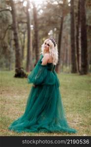 young beautiful blonde hair woman queen. Princess walks. autumn green forest mystic. Vintage medieval shiny crown. Long evening green dress. magic fantasy. back view.. young beautiful blonde hair woman queen. Princess walks. autumn green forest mystic. Vintage medieval shiny crown. Long evening green dress. magic fantasy. back view