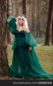 young beautiful blonde hair woman queen. Princess walks. autumn green forest mystic. Vintage medieval shiny crown. Long evening green dress. magic fantasy.. young beautiful blonde hair woman queen. Princess walks. autumn green forest mystic. Vintage medieval shiny crown. Long evening green dress. magic fantasy