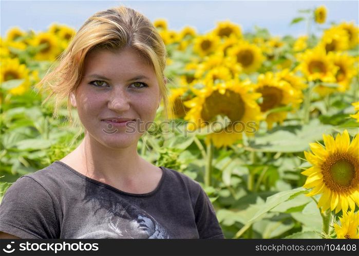 Young beautiful blonde in sunflower flowers. Girl in the field of sunflowers.. Young beautiful blonde in sunflower flowers. Girl in the field of sunflowers