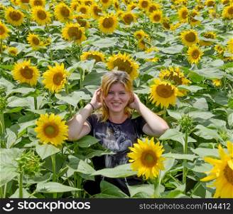 Young beautiful blonde in sunflower flowers. Girl in the field of sunflowers.. Young beautiful blonde in sunflower flowers. Girl in the field of sunflowers