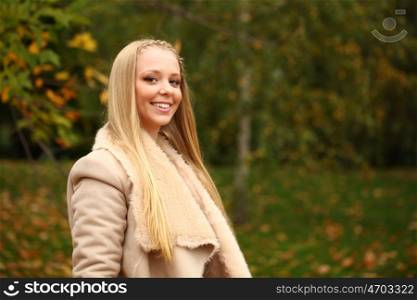 Young beautiful blonde women in a leather sheepskin coat on golden autumn background