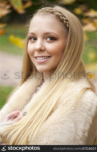Young beautiful blonde women in a leather sheepskin coat on golden autumn background