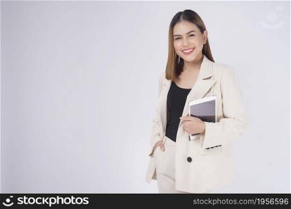 Young beautiful businesswoman in suit holding tablet over white Studio background