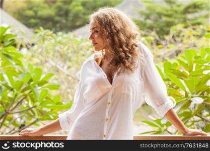 Young beautiful casual dressed girl wearing white shirt in tropical garden on a sunny day. Girl in tropical garden