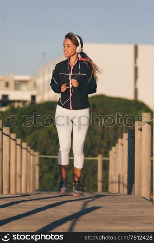 Young beautiful chinese woman exercising at the beach at sunrise/sunset