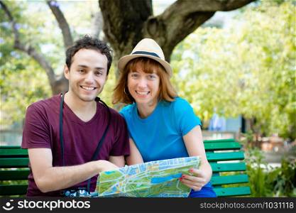 Young beautiful couple holding map in hands and traveling together. Tourism concept. Outdoors.