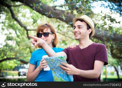 Young beautiful couple holding map in hands and traveling together. Tourism concept. Outdoors.