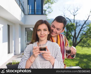 Young beautiful couple in bathrobes are enjoying morning coffee in front of their luxury home villa