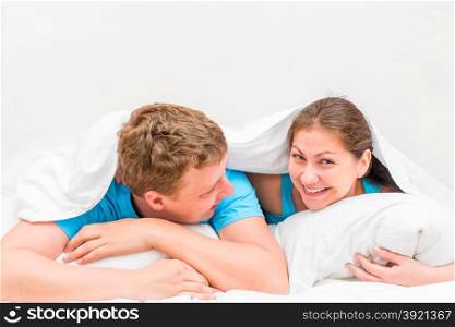 Young beautiful couple in bed under a blanket