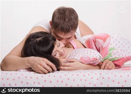 Young beautiful couple kissing and embracing in bed