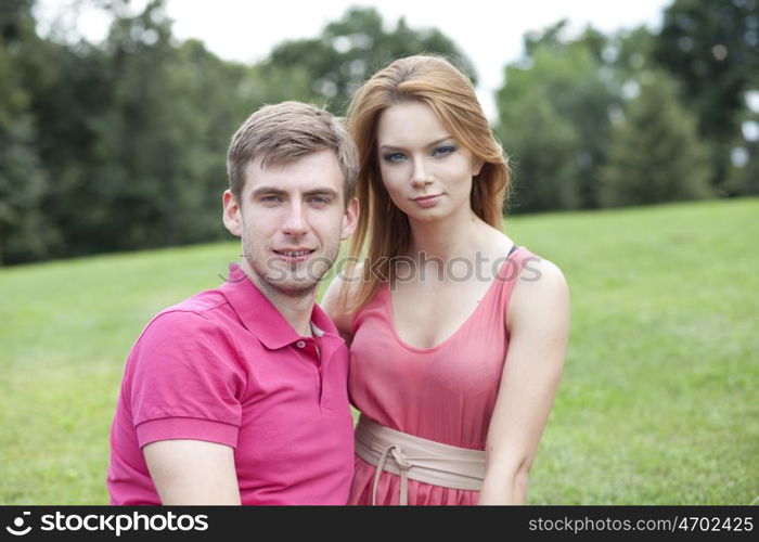 Young beautiful couple lovers, against green of summer park.